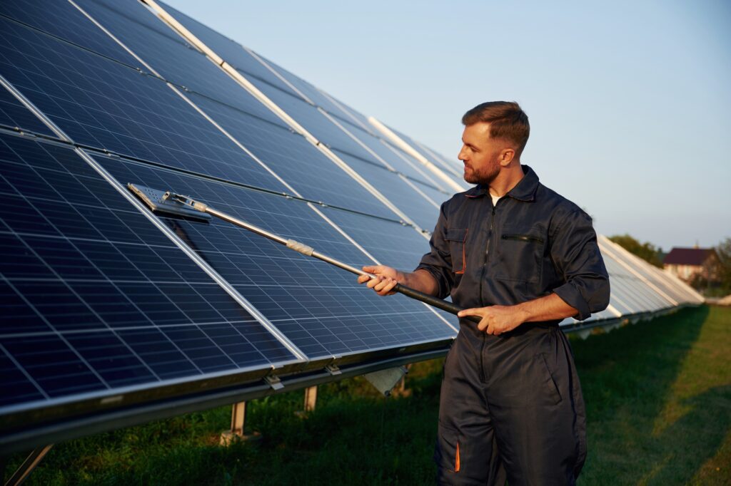 Keep it clean. Man is working with solar panels outdoors at daytime